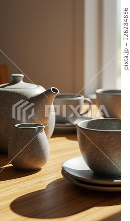 Morning light on ceramic teapot and cup set in cozy kitchen scene Morning light on ceramic teapot and cup set in cozy kitchen scene 126284886