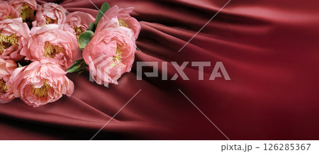 An Elegant Arrangement of Delicate Pink Flowers Set on a Luxurious Crimson Silk Background 126285367