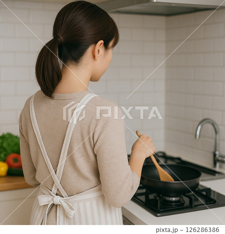 キッチンで調理をするエプロン姿の女性 キッチンで調理をするエプロン姿の女性 126286386