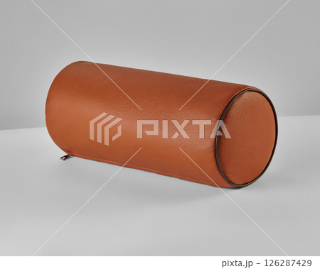 Cylindrical leather cushion resting on white surface 126287429