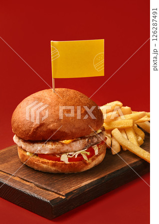 Delicious burger with french fries and yellow flag on red background 126287491
