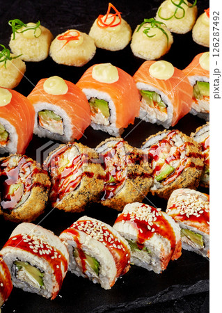 Sushi set displayed on black stone featuring variety of rolls and toppings 126287492