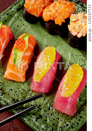 Delicious sushi assortment with chopsticks on green plate: vibrant japanese cuisine Delicious sushi assortment with chopsticks on green plate: vibrant japanese cuisine 126287515
