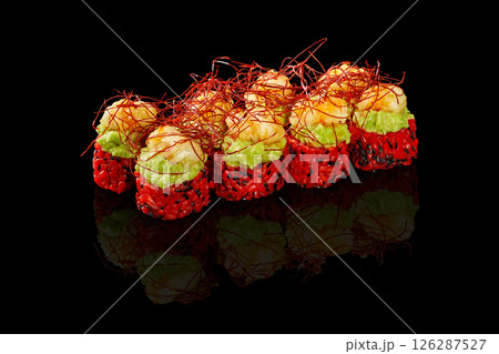 Delicious red sushi rolls topped with shrimp and guacamole with saffron reflecting on black background 126287527