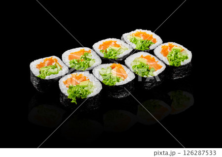 Sushi rolls with salmon, avocado, salad and fish eggs reflecting on black background 126287533