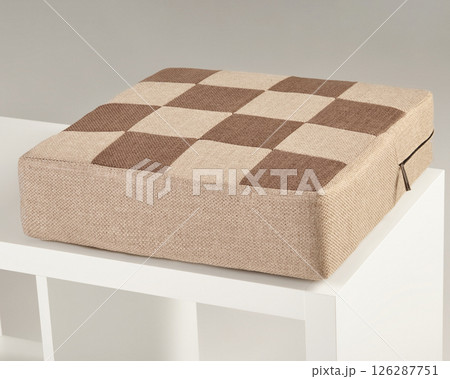 Checkered brown and beige seat cushion resting on white shelf 126287751