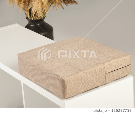 Beige fabric cushion resting on modern white bench Beige fabric cushion resting on modern white bench 126287752