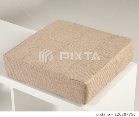 Beige fabric padded seat cushion resting on white shelf Beige fabric padded seat cushion resting on white shelf 126287753