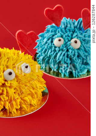 Two funny colorful monster cakes showing love on red background 126287844
