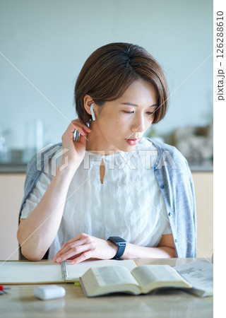 イヤホンをつけて勉強をする女性 126288610