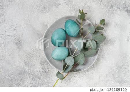 Easter colored eggs, in turquoise tones, on a gray plate, with a branch of eucalyptus, Easter card, top view, no people 126289199