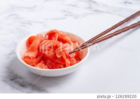 Pickled ginger, with chopsticks, in a small white bowl, on a marble countertop, close-up, no people, 126289220