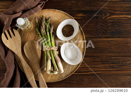 Asparagus spears, salt, pepper, oil and wooden utensils on rustic table. Top view 126289610