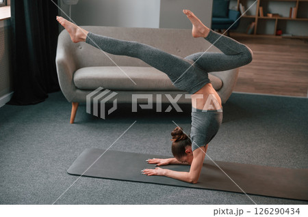 Making handstand. Young woman in yoga clothes doing fitness indoors 126290434