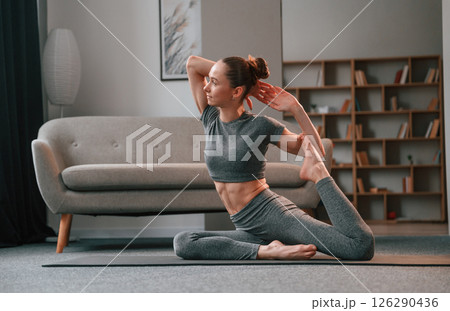 Stretching the legs. Young woman in yoga clothes doing fitness indoors 126290436
