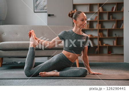 Stretching the legs. Young woman in yoga clothes doing fitness indoors 126290441