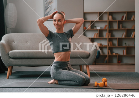 Sitting on the mat. Young woman in yoga clothes doing fitness indoors Sitting on the mat. Young woman in yoga clothes doing fitness indoors 126290446