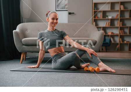 Relaxed, on the mat. Young woman in yoga clothes doing fitness indoors 126290451