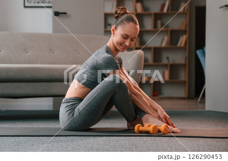 In apartment. Young woman in yoga clothes doing fitness indoors 126290453