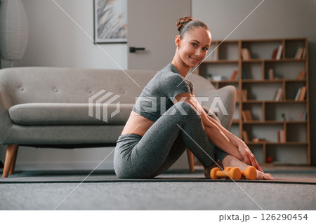 Relaxed, on the mat. Young woman in yoga clothes doing fitness indoors Relaxed, on the mat. Young woman in yoga clothes doing fitness indoors 126290454