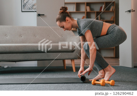Rolling off the mat. Young woman in yoga clothes doing fitness indoors 126290462
