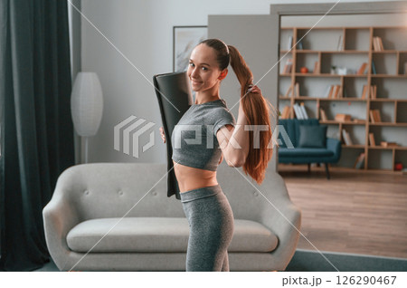 Posing, holding mat. Young woman in yoga clothes doing fitness indoors 126290467