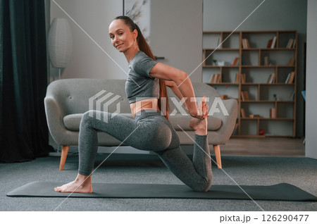 Side view. Young woman in yoga clothes doing fitness indoors 126290477
