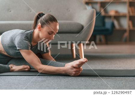 Focused on stretching exercise. Young woman in yoga clothes doing fitness indoors 126290497