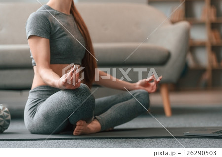 Sitting in lotus pose. Young woman in yoga clothes doing fitness indoors Sitting in lotus pose. Young woman in yoga clothes doing fitness indoors 126290503