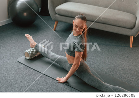 Big stretch for legs. Young woman in yoga clothes doing fitness indoors Big stretch for legs. Young woman in yoga clothes doing fitness indoors 126290509