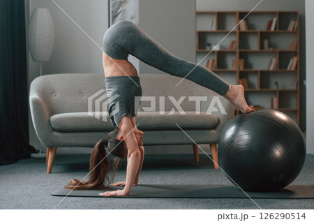 Using fitness ball. Young woman in yoga clothes doing fitness indoors Using fitness ball. Young woman in yoga clothes doing fitness indoors 126290514