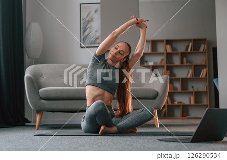 Warm up exercises. Young woman in yoga clothes doing fitness indoors Warm up exercises. Young woman in yoga clothes doing fitness indoors 126290534