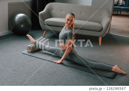 Leg are on the foam roller. Young woman in yoga clothes doing fitness indoors Leg are on the foam roller. Young woman in yoga clothes doing fitness indoors 126290567