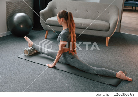 Big stretch for legs. Young woman in yoga clothes doing fitness indoors Big stretch for legs. Young woman in yoga clothes doing fitness indoors 126290568