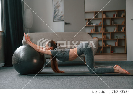Using fitness ball. Young woman in yoga clothes doing fitness indoors Using fitness ball. Young woman in yoga clothes doing fitness indoors 126290585