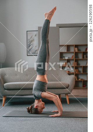 Making headstand. Young woman in yoga clothes doing fitness indoors 126290598