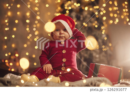 In Santa hat. Cute little baby is at home. New year decorations. Conception of holidays 126291077