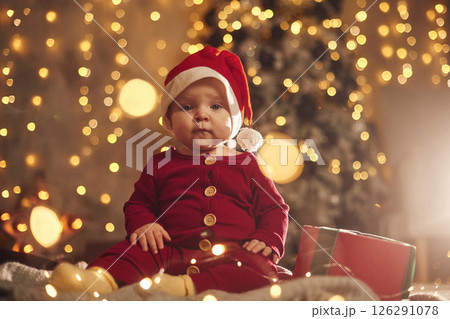 In Santa hat. Cute little baby is at home. New year decorations. Conception of holidays 126291078