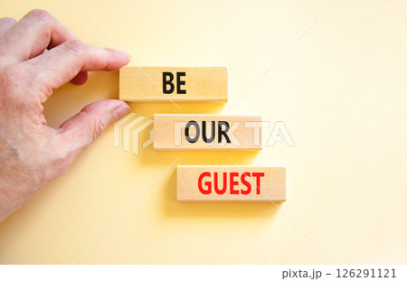 Be our guest symbol. Concept words Be our guest on beautiful wooden block. Businessman's hand. Beautiful white background. Business and be our guest concept. Copy space. 126291121