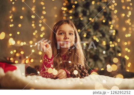 Cute little girl is lying down on the floor at home, celebrating New Year Cute little girl is lying down on the floor at home, celebrating New Year 126291252