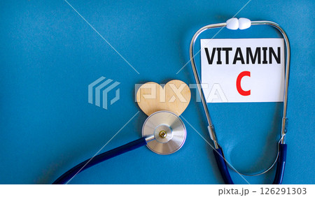Vitamin C symbol. Concept words Vitamin C on beautiful white card. Wooden heart and stethoscope. Beautiful blue background. Medical healthy lifestyle Vitamin C concept. 126291303