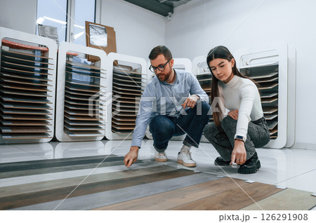 Sitting and choosing parquet. Woman and man is in the store of goods for the home Sitting and choosing parquet. Woman and man is in the store of goods for the home 126291908