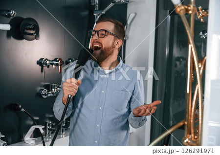 Playing with shower faucet, singing. Man chooses a products in a sanitary ware store 126291971