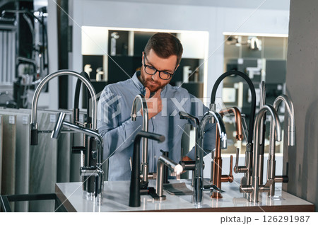 A large selection of water faucets. Man chooses a products in a sanitary ware store 126291987