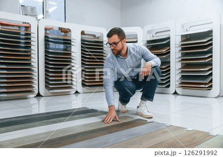 Sitting and choosing parquet. Man is in the store of goods for the home 126291992