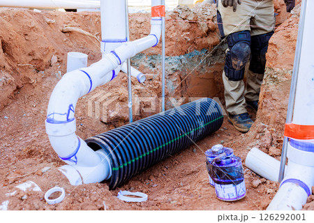 Workers install sewage drainage system in trench, plumbing materials construction during installation progress Workers install sewage drainage system in trench, plumbing materials construction during installation progress 126292001