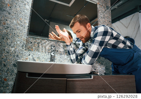 Can't fix the crane. Plumber in blue uniform is at work in the bathroom 126292028