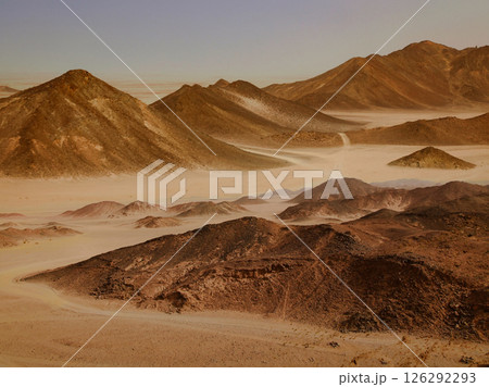Panoramic view of desert mountains and valleys, creating a stunning arid landscape scene. A scenic view of a sandy landscape with majestic mountains. Panoramic view of desert mountains and valleys, creating a stunning arid landscape scene. A scenic view of a sandy landscape with majestic mountains. 126292293