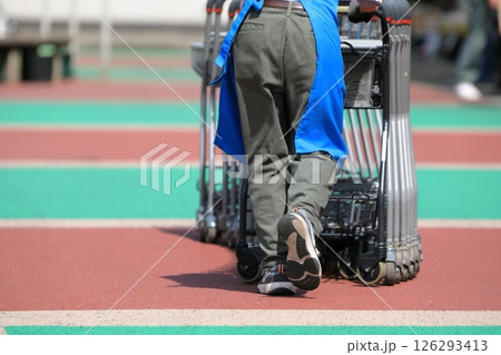 ショッピングカートの列を押すスタッフ ショッピングカートの列を押すスタッフ 126293413