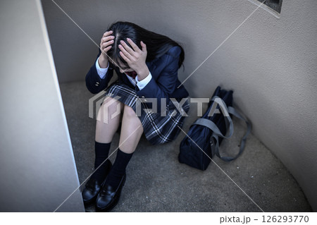 階段の踊り場でしゃがみ込む女子高生　頭を抱える　いじめ　不登校　将来の不安　 126293770